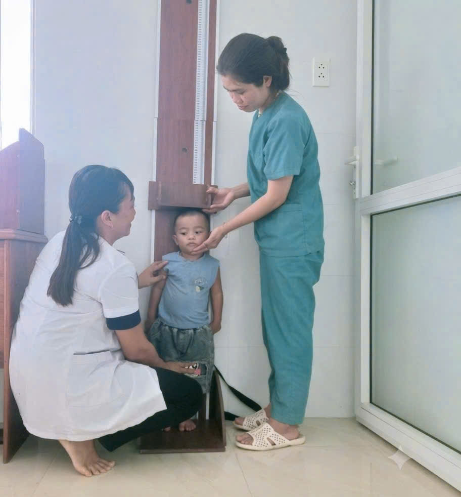 Cán bộ y tế thực hiện đo chiều cao cho trẻ em tại xã Chư A Thai.